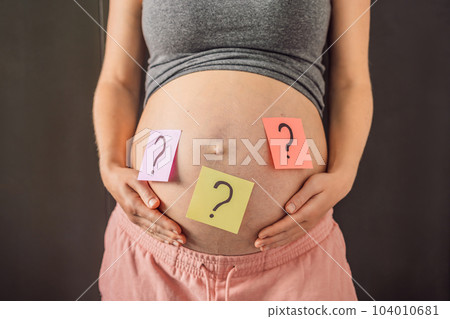 Choosing baby name. Confused pregnant woman with question marks on paper stickers on tummy Choosing baby name. Confused pregnant woman with question marks on paper stickers on tummy 104010681