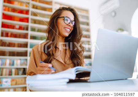 Online conference, training Student girl working with laptop, learning in college library. Freelance Online conference, training Student girl working with laptop, learning in college library. Freelance 104011597