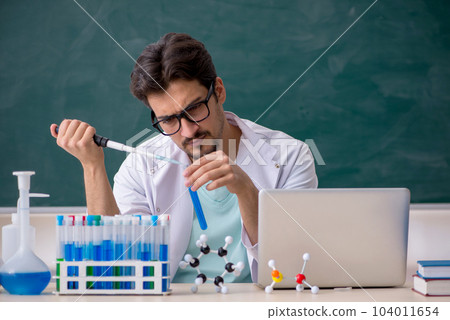 Young male chemist in front of blackboard Young male chemist in front of blackboard 104011654