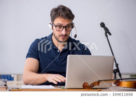 Young male music teacher sitting in the classroom Young male music teacher sitting in the classroom 104011698