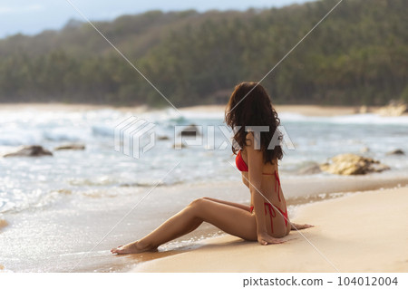 Contemplative Beach Getaway Young Woman in Swimsuit Gazing out at the Ocean 104012004