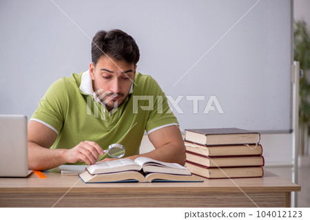 Young male student sitting in front of whiteboard Young male student sitting in front of whiteboard 104012123