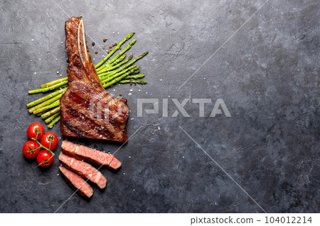 Medium rare grilled Tomahawk beef steak with asparagus Medium rare grilled Tomahawk beef steak with asparagus 104012214