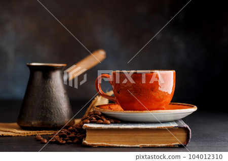 Rich coffee in a cup with aromatic roasted beans 104012310