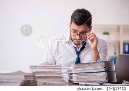 Young male employee and too much work in the office 104012680