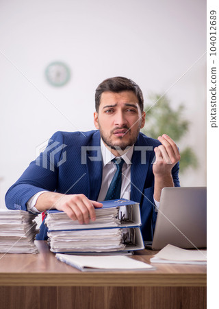 Young male employee and too much work in the office 104012689