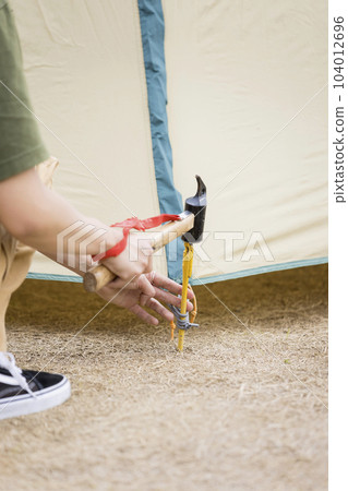 Young woman setting up a tent 104012696