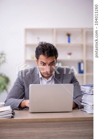 Young male employee and too much work in the office 104013260