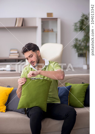 Young man with a lot of pillows sitting on the sofa 104013342