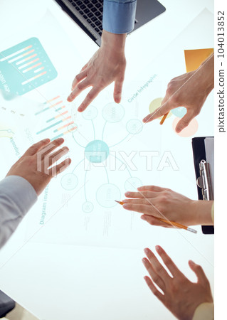 Human hands during the conference in office over illuminated desk with graphs, charts, tables. Brainstorming 104013852