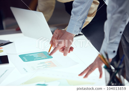 Closeup businessmen hands during business meeting in technology research laboratory. Co-workers gathered around illuminated conference table. 104013859