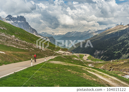 Cyclist on Klausen pass road, mountain panorama in the Swiss Alps, Switzerland 104015122