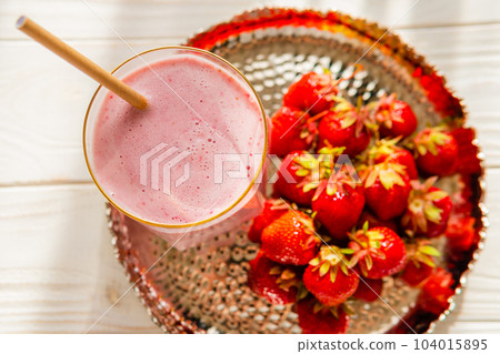 Fresh Milkshake or smoothie in glass with strawberries on wooden table, close up Fresh Milkshake or smoothie in glass with strawberries on wooden table, close up 104015895