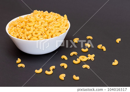 Uncooked Chifferi Rigati Pasta in Glass Jar on Black Background Uncooked Chifferi Rigati Pasta in Glass Jar on Black Background 104016317