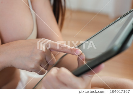Close up tablet, woman using digital tablet at home in bedroom. cute beauty woman relax Close up tablet, woman using digital tablet at home in bedroom. cute beauty woman relax 104017367