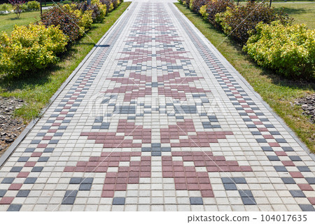 A beautiful path paved with paving slabs in the form of an embroidered Ukrainian ornament. A beautiful path paved with paving slabs in the form of an embroidered Ukrainian ornament. 104017635