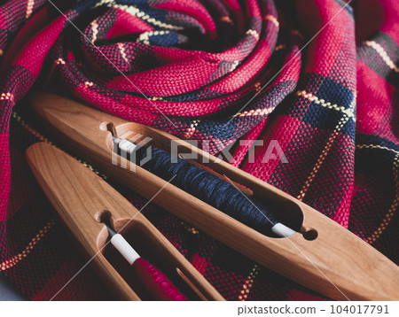 Two boat shuttles and handwoven fabric in red and black colors, close up. Ready weaving project Two boat shuttles and handwoven fabric in red and black colors, close up. Ready weaving project 104017791