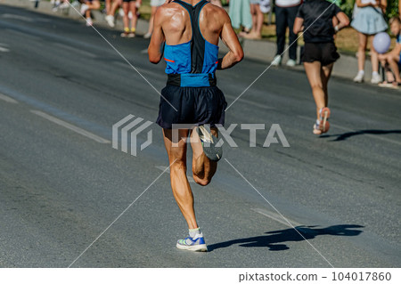 rear view male runner running city marathon, hot weather sweat on his back rear view male runner running city marathon, hot weather sweat on his back 104017860