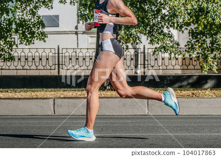 side view female runner athlete running city marathon race, summer sports games 104017863