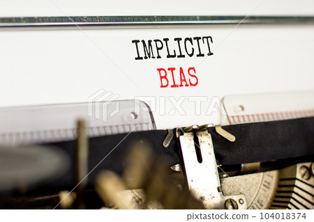 Implicit bias symbol. Concept words Implicit bias typed on white paper on old retro typewriter. Beautiful white background. Business psychology implicit bias concept. Copy space. 104018374