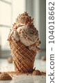 Vertical appetizing caramel ice cream on the table. Dessert. Ice cream in a waffle cup melts while standing on a white table, surrounded by waffle crumbs 104018662
