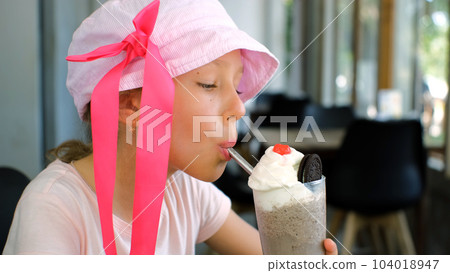Little girl drinking chocolate milkshake while resting at cafe or restaurant Little girl drinking chocolate milkshake while resting at cafe or restaurant 104018947