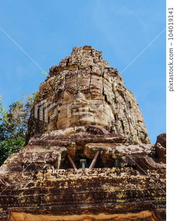 A stone statue of a portrait of a man on the tower of the Ta Prohm temple in Cambodia. 104019141