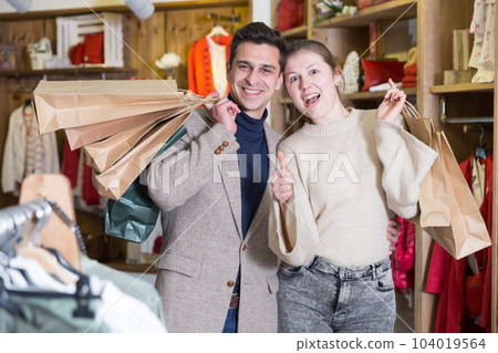 Smiling couple is satisfied of purchases and standing with package 104019564
