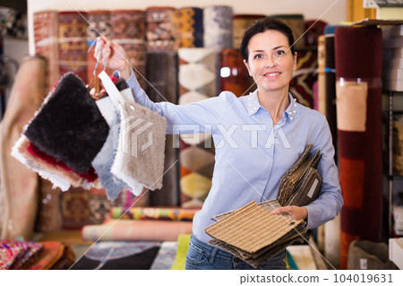 Glad woman shopping carpet and showing samples 104019631