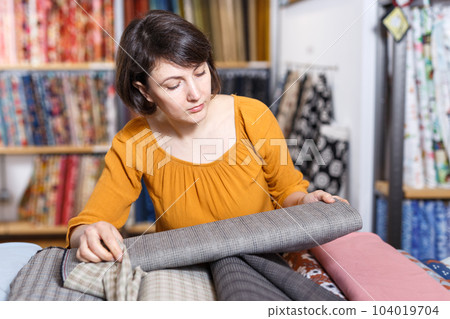 Brunette choosing fabric in store Brunette choosing fabric in store 104019704