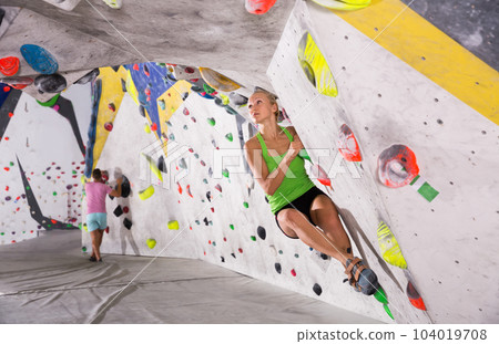 Woman climbing artificial rock in gym 104019708