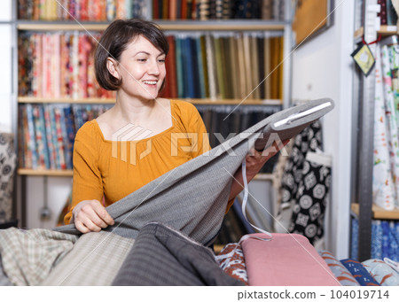 Happy woman choosing textiles 104019714