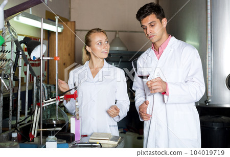 Winery workers in white robes controlling fermantation 104019719
