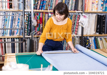 Saleswoman measuring cloth for cutting Saleswoman measuring cloth for cutting 104019721