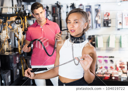 Girl and man choosing black collar in sex shop Girl and man choosing black collar in sex shop 104019722