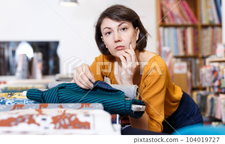 Brunette choosing fabric in store Brunette choosing fabric in store 104019727