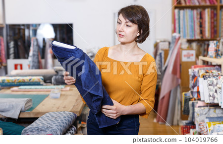Brunette choosing fabric in store Brunette choosing fabric in store 104019766