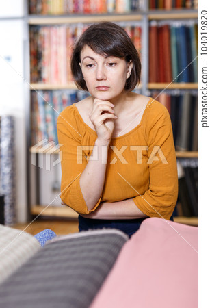 Pensive female customer in cloth store Pensive female customer in cloth store 104019820