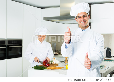 Male cook showing thumb up, woman cook on background 104019832