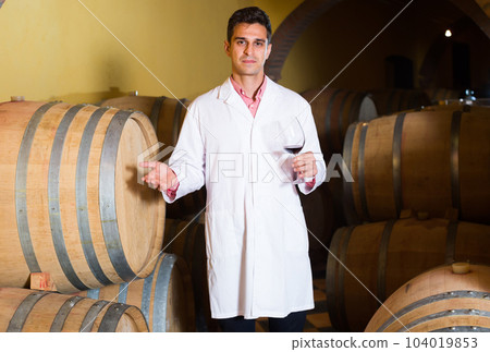 taster of winery with wine in cellar. 104019853