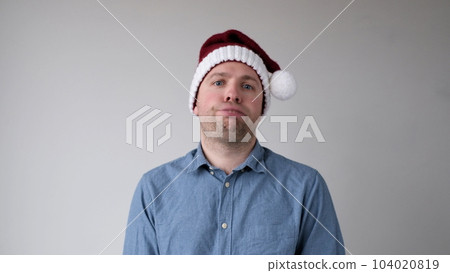 The sad and sorrowful European young man in a New Year's hat looks gloomily into the camera. Disappointments in the New Year celebration 104020819