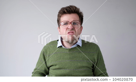 European young man with poor vision peers through his glasses, trying to discern the information that interests him 104020870