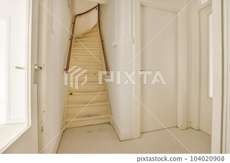 an empty room with stairs leading up to the second floor and another door in the corner, which is partially closed 104020908