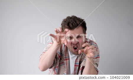 European young man frightens the interlocutor, says boo, and contorts his fingers 104021009