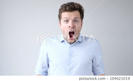 European young man is greatly surprised and opens his mouth in astonishment European young man is greatly surprised and opens his mouth in astonishment 104021019