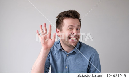 European young man waves his hand, greets his friends. 104021049