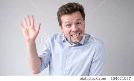 European young man waves his hand, greets his friends. European young man waves his hand, greets his friends. 104021057