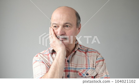 Very bored senior adult man holding hand on cheek , looking tired and sick Very bored senior adult man holding hand on cheek , looking tired and sick 104021102
