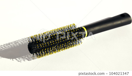 Round black hairbrush on a white background. Hair care concept. Round black hairbrush on a white background. Hair care concept. 104021347