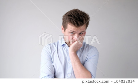 man is looking thoughtfully into the camera, perplexed by a difficult choice 104022034